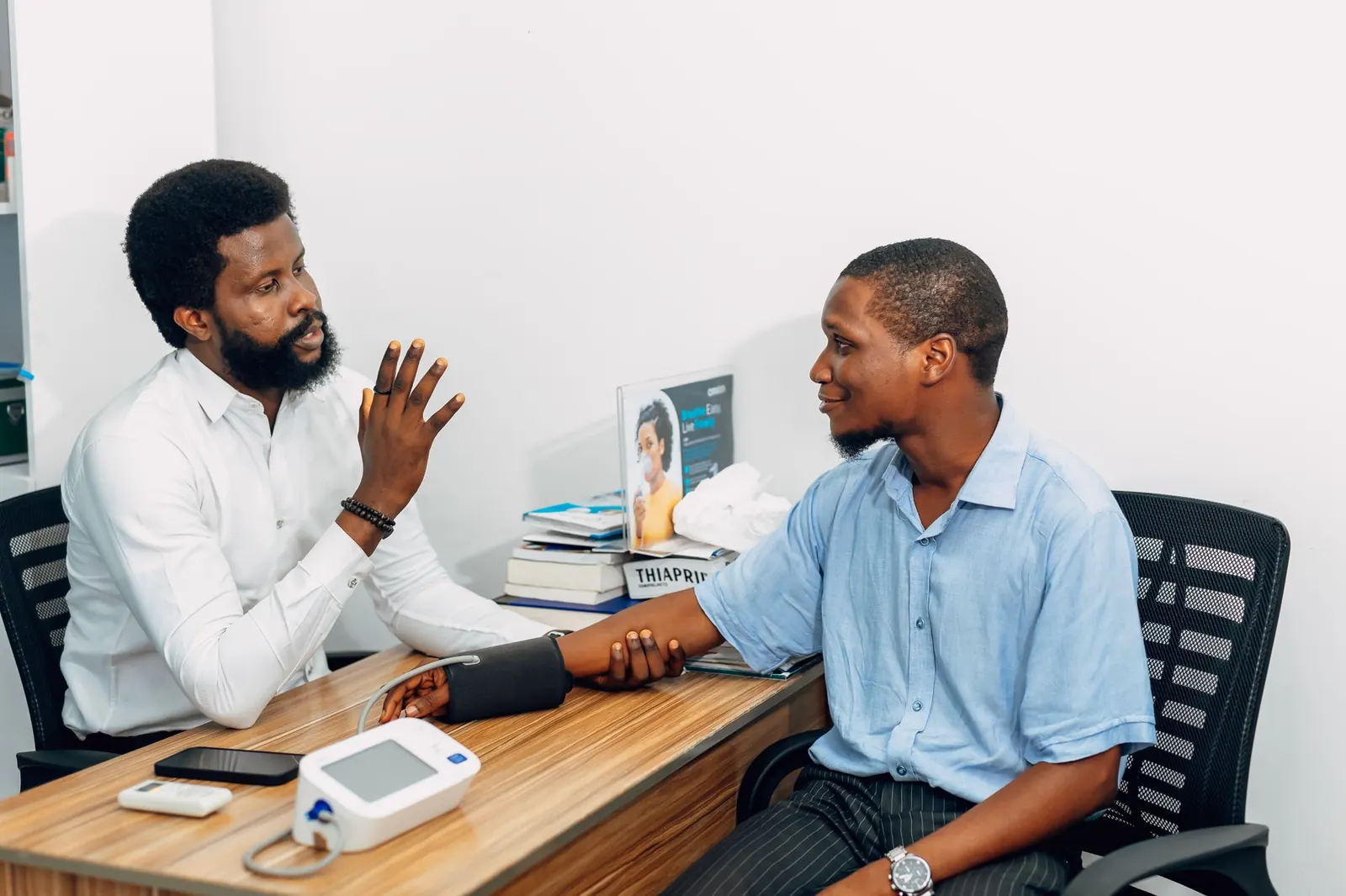 Doctor talking a patient through his blood pressure reading at a consultation desk